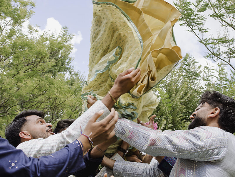 Guests joyfully lifting a participant during the Haldi ceremony in Rome, captured at Hotel Roma Life Style by Cossu Photography.