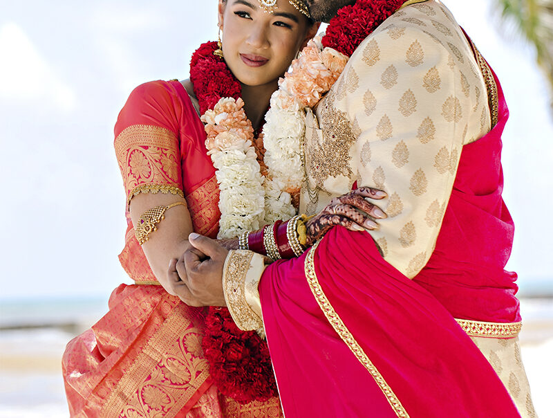 Indian bride and groom embracing on a beach in Italy during a Hindu destination wedding
