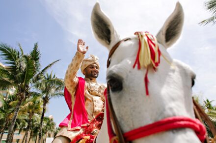 Indian groom riding a horse during the baraat procession at a luxury Hindu wedding in Tuscany, Italy